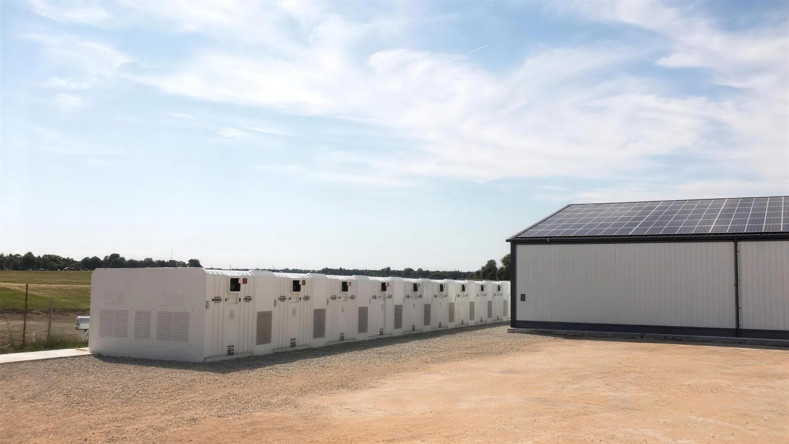 Batteriespeicher-Container neben einer Industriehalle mit Solardach
